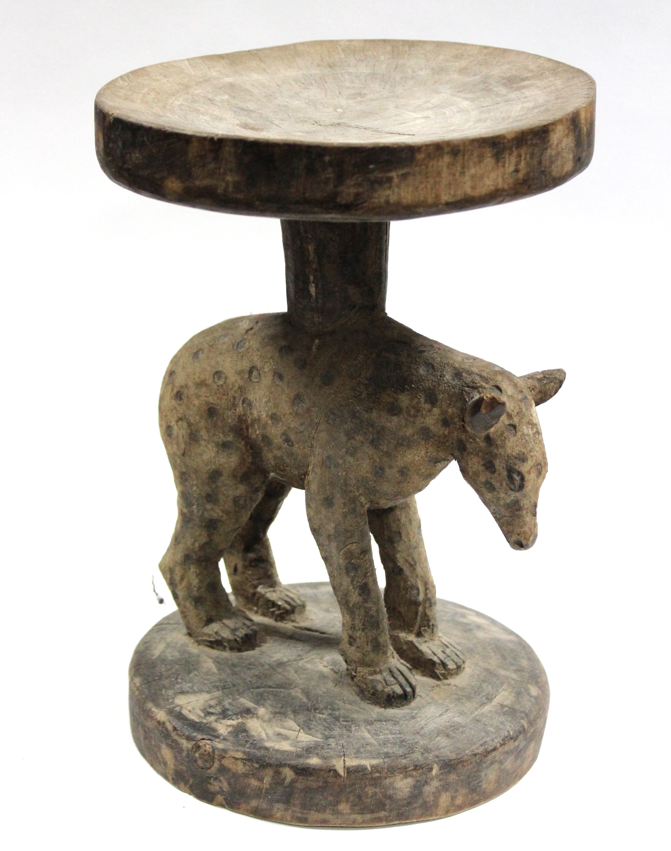 A Zimbabwean carved wooden stool, Tonga, the circular hard seat supported by a spotted hyena on