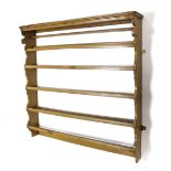 An early 18th century wall-mounted plate rack of three open shelves, painted in ochre, 40½” wide x