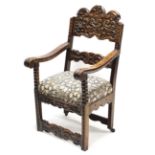 A 17th century-style Spanish carved walnut armchair with shaped back, scroll arms, padded seat, &