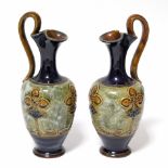 A pair of Royal Doulton stoneware ewers with art nouveau stylised floral motifs; 9½” high.