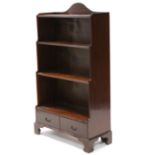 A regency-style mahogany “waterfall” open bookcase with shaped top, fitted two shelves above two