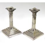 A pair of candlesticks by William Hutton & Sons, the stop-fluted Corinthian columns on square