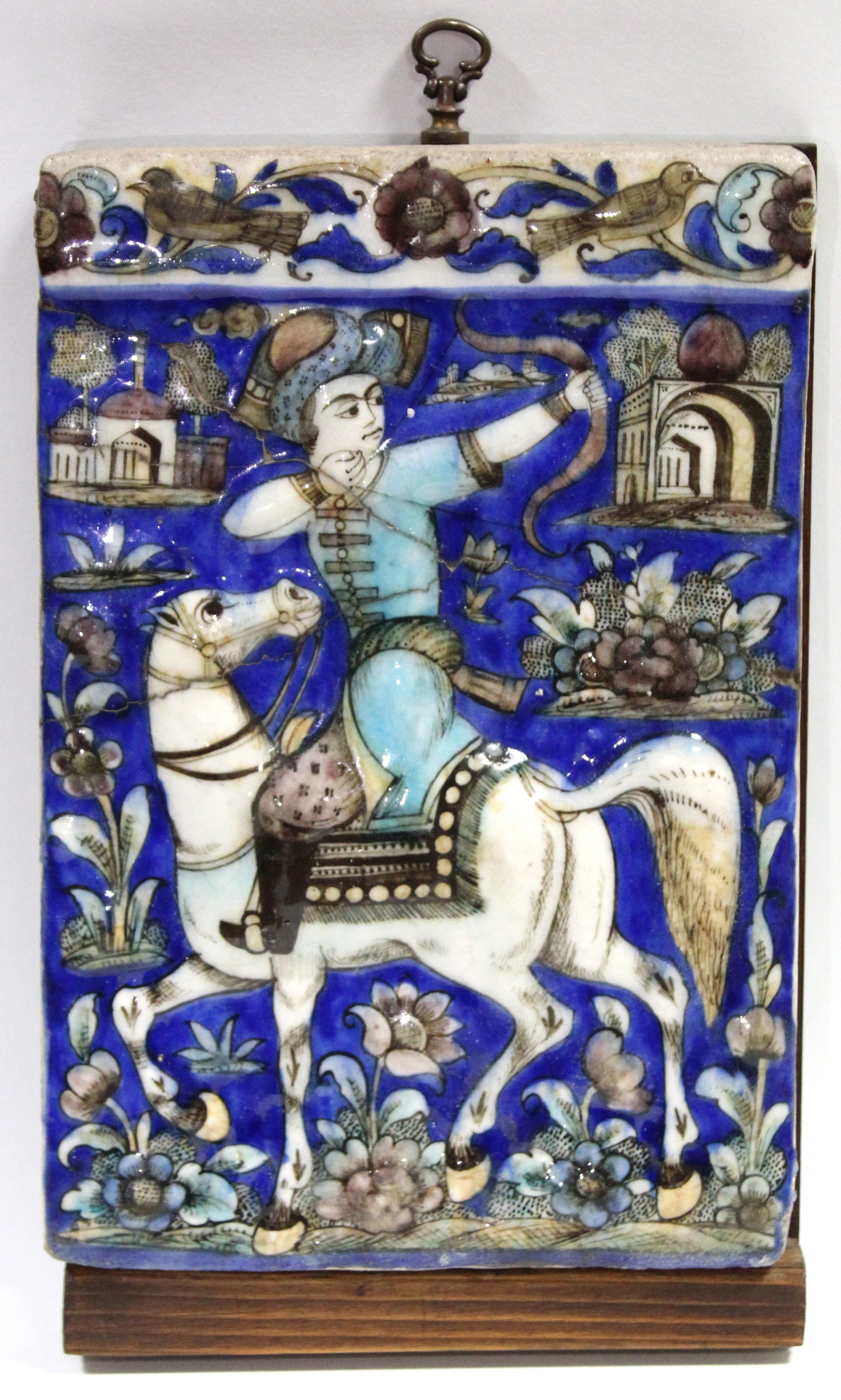 A late 19th century Qajar moulded pottery tile decorated with an equestrian archer surrounded by