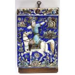 A late 19th century Qajar moulded pottery tile decorated with an equestrian archer surrounded by