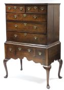 AN 18th century OAK CHEST-ON-STAND, with moulded cornice, fitted two short & three long graduated