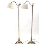 A pair of brass standard lamps, each with scroll arm on turned column & triform base with lion-paw
