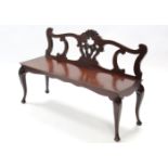 An 18th century-style mahogany hall bench with pierced shaped back, hard seat, & on slender cabriole