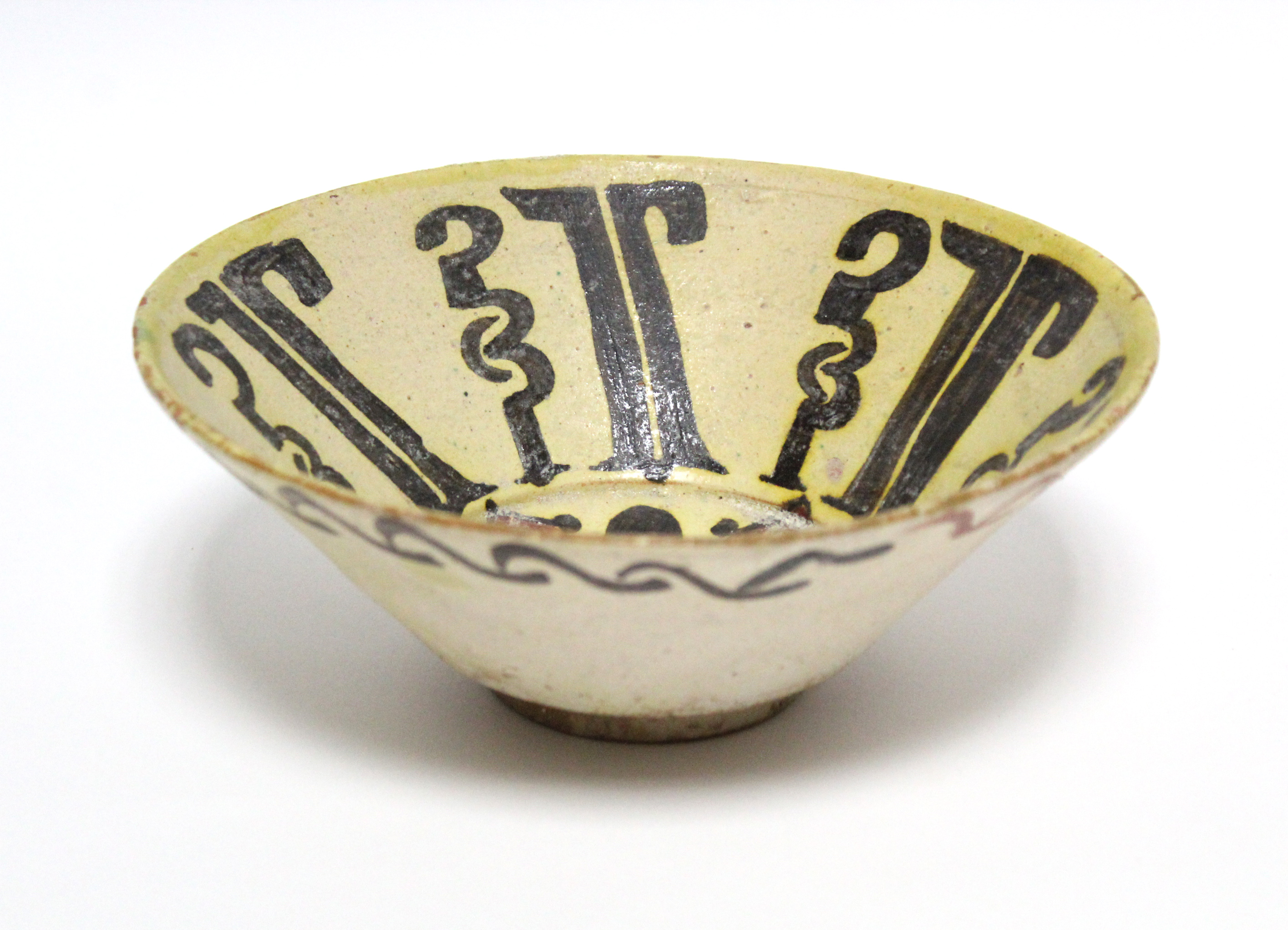 An early Persian pottery deep dish of pale yellow ground, decorated with stylised motifs in