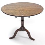 A 19th century oak tripod table with circular tilt-top, & on vase-turned centre column & three