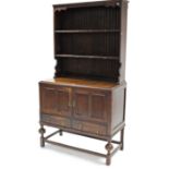 A mid-20th century oak dresser, the upper part fitted two open shelves & with panelled back, the