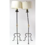 A pair of wrought-iron & brass standard lamps on triform bases, complete with shades (slight