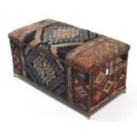 A wooden ottoman, upholstered in Persian pattern material & on brass castors, (slight faults), 36”