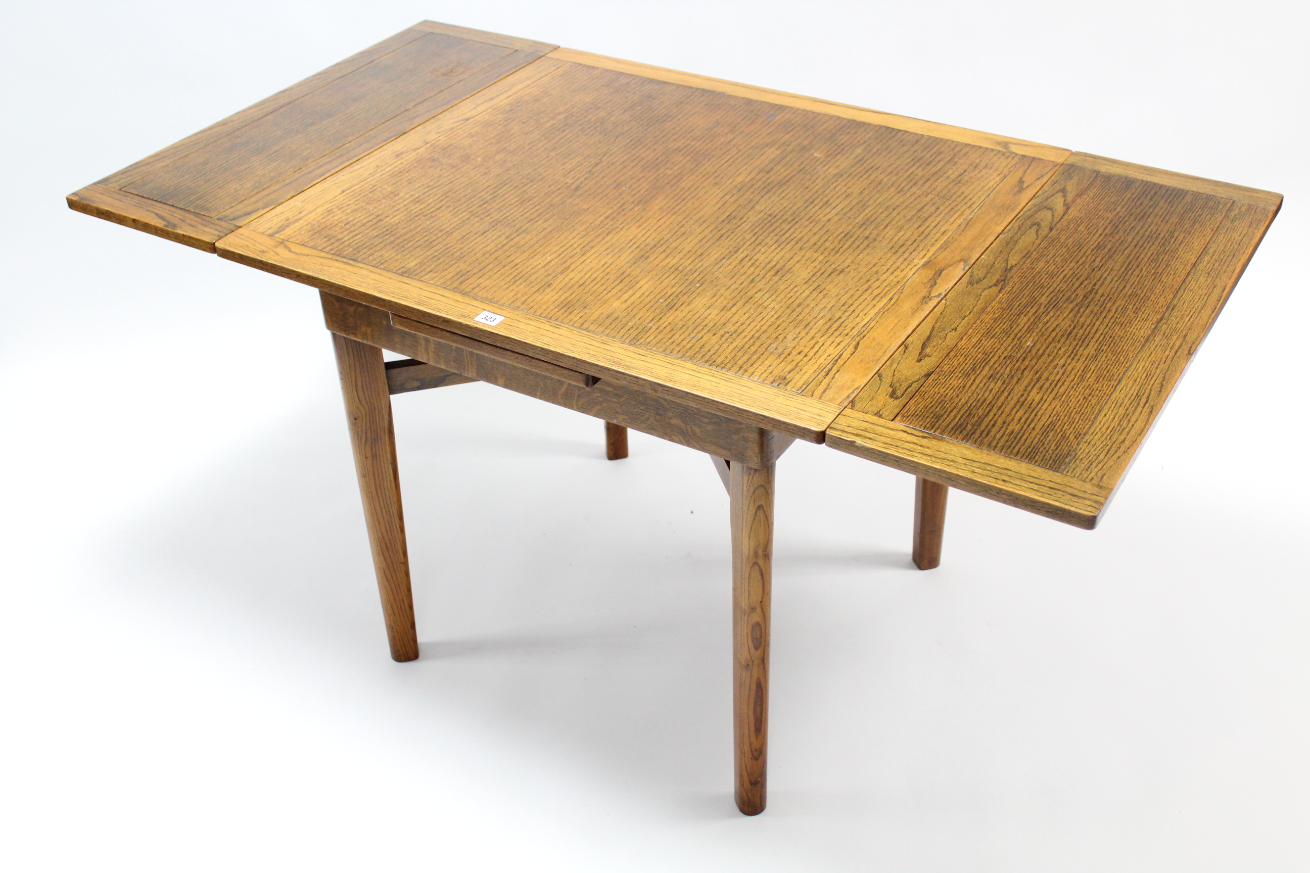 A mid-20th century oak draw-leaf dining table on square tapered legs with diagonal stretchers,