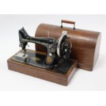 A Singer hand sewing machine in oak case.