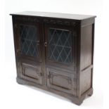 A reproduction carved oak small bookcase, enclosed by pair of leaded glazed doors above cupboard