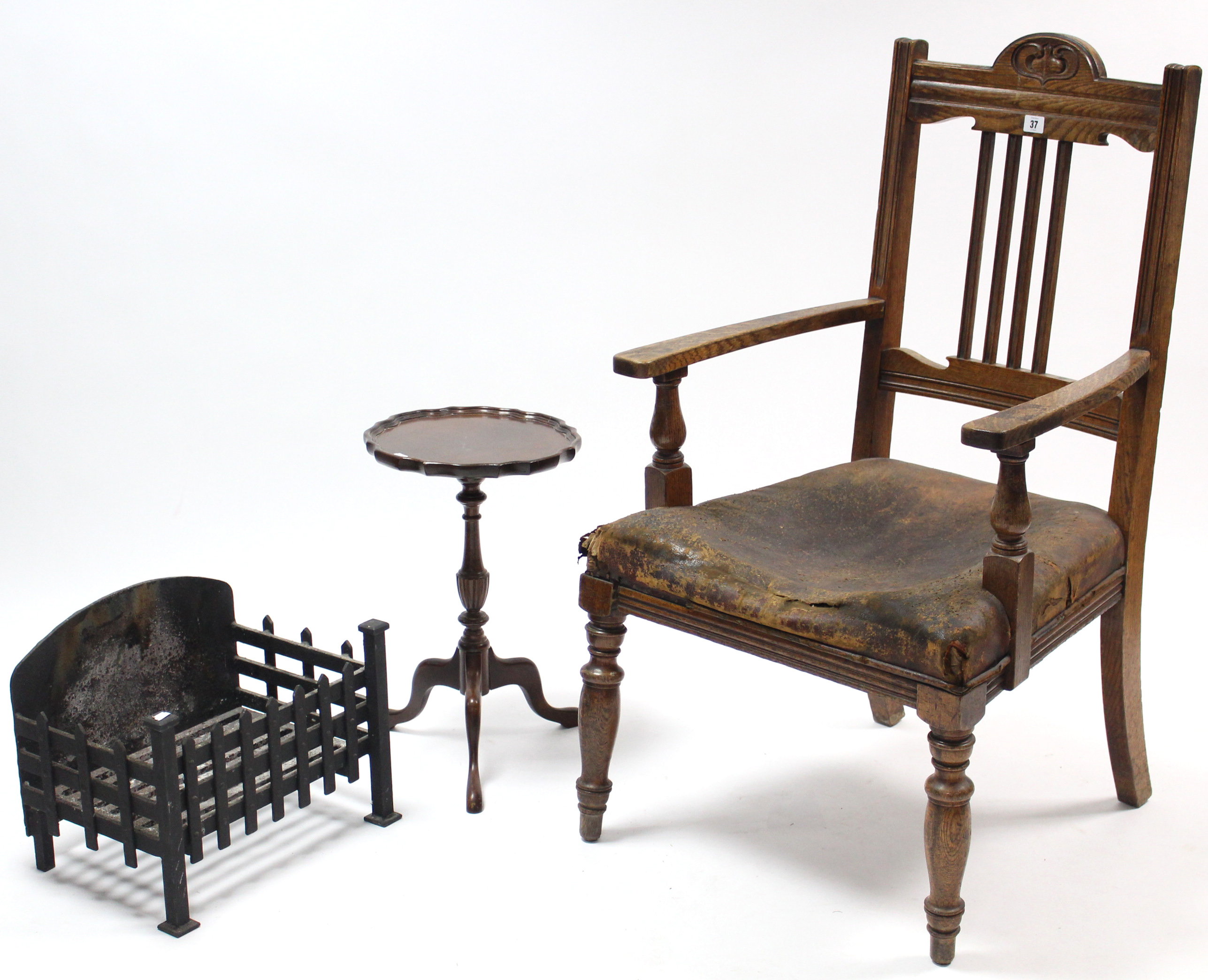 A late Victorian carved oak rail-back elbow chair (w.a.f.); together with a cast-iron fire basket,
