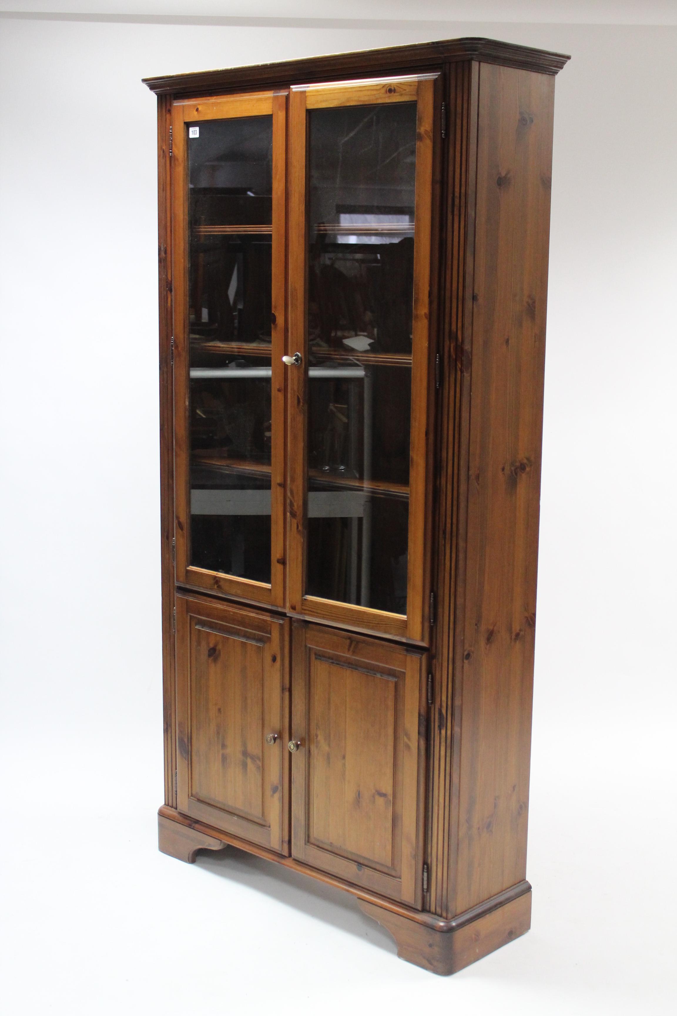 A Ducal pine tall cabinet, fitted five shelves enclosed by two pairs of doors, & on bracket feet,