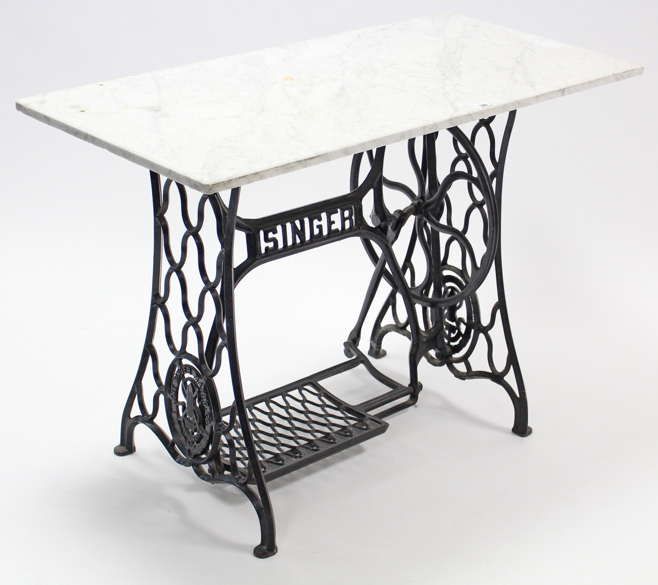 A Singer cast-iron treadle-sewing machine base with white-marble top, 42” wide.