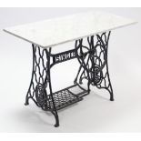A Singer cast-iron treadle-sewing machine base with white-marble top, 42” wide.