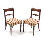 A pair of Regency carved mahogany bow-back dining chairs with padded seats & turned tapering legs.