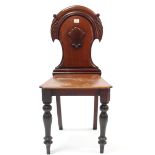 A Victorian mahogany hall chair with carved & shaped panel back, with hard seat, & on baluster-