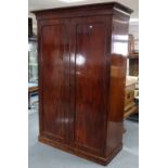 A Victorian mahogany wardrobe with moulded cornice, enclosed by pair of panel doors, & on plinth