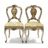 A pair of 19th century French cream & gilt painted salon chairs with rococo-style foliate carving,