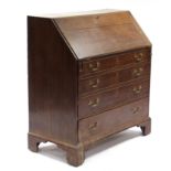 A late 18th century oak bureau, the sloping fall-front enclosing a fitted interior, four long
