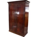 A Victorian mahogany wardrobe with moulded cornice, enclosed by pair of panel doors, & on plinth