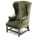 A George III-style wing-back armchair upholstered dark green velour, on square legs with plain