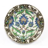 A 17th century IZNIK POTTERY SHALLOW DISH with polychrome painted stylised floral decoration