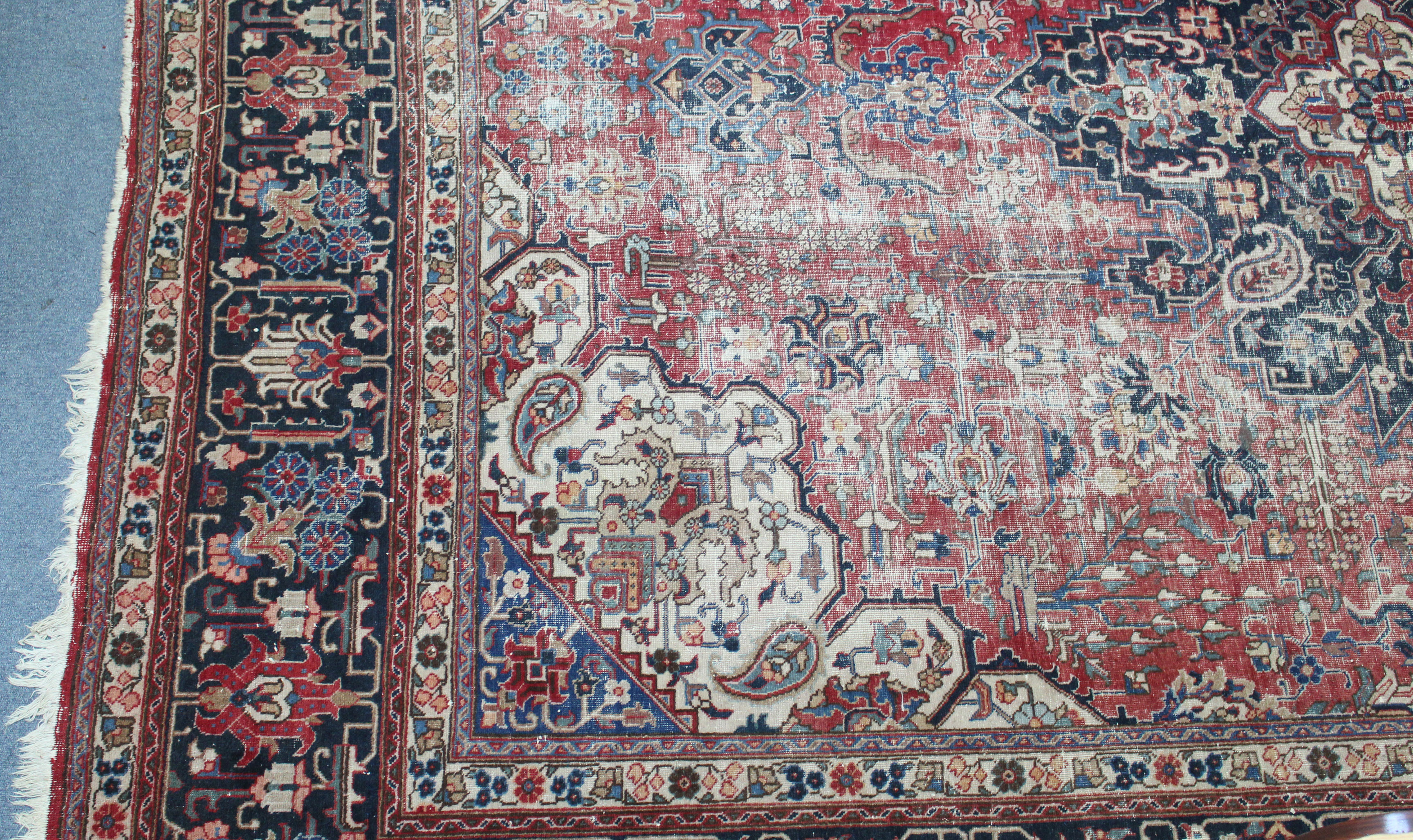 An antique Persian carpet of crimson, deep blue & ivory ground, with central medallion surrounded by