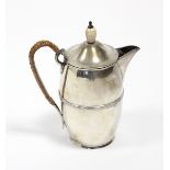 An Edwardian silver hot water jug of slender ovoid shape with reeded band around the girth, cane-