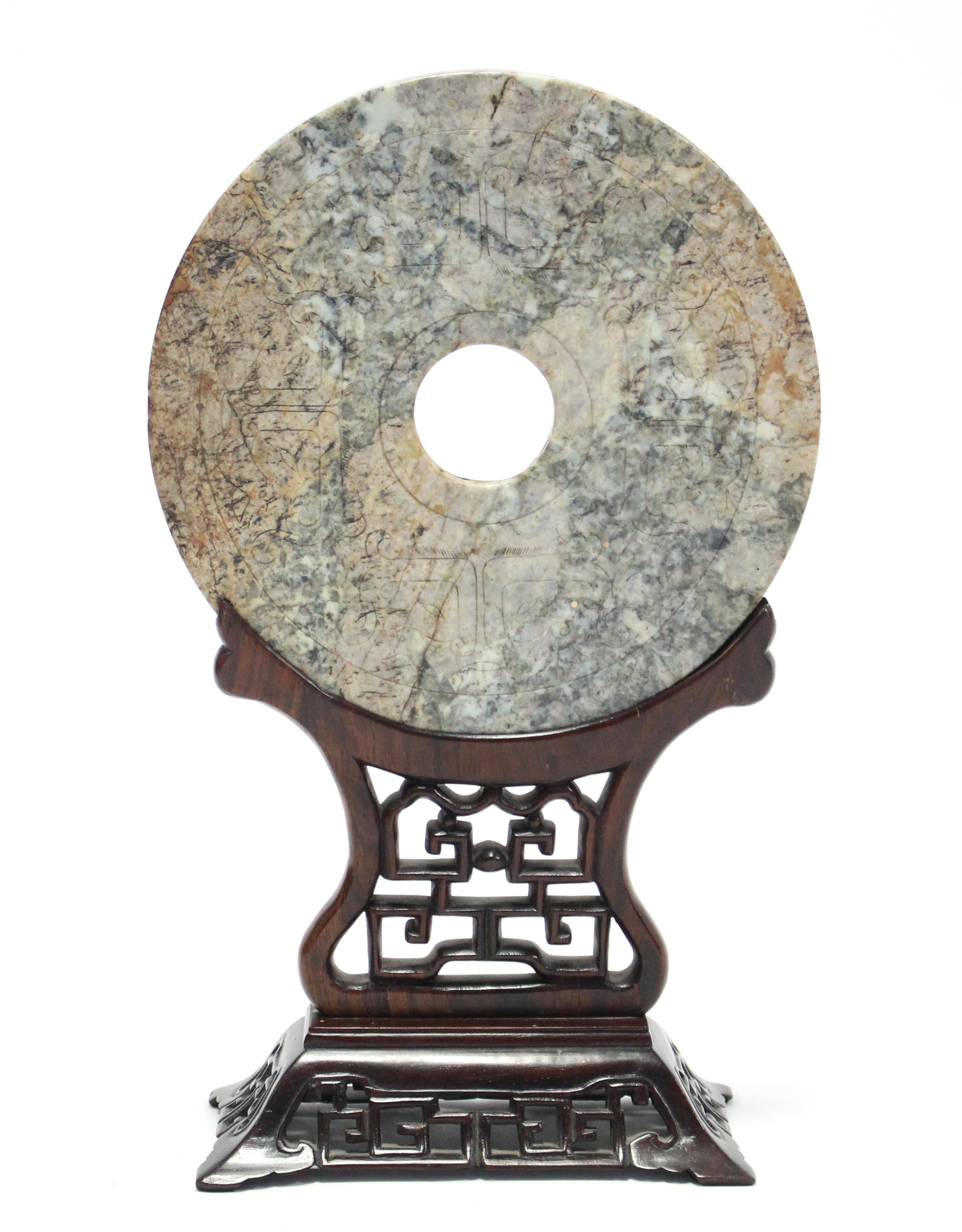 A CHINESE ARCHAISTIC CARVED JADE DISC (BI), the stone of mottled green, russet, & grey tone, the