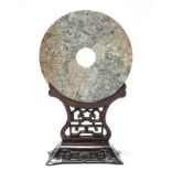 A CHINESE ARCHAISTIC CARVED JADE DISC (BI), the stone of mottled green, russet, & grey tone, the