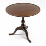 A mid-18th century mahogany tripod table, the circular tilt-top with raised edge, on baluster-turned