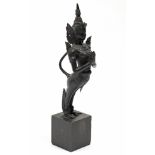 A Thai bronze standing figure of Kinnara with hands in prayer; 15¾” high, on wooden block base.