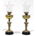 A pair of Victorian gilt-brass oil lamps, the columns in the form of two putti supporting an urn,