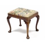 An 18th century walnut rectangular stool, the padded drop-in seat upholstered floral needlework,