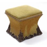 A Victorian upholstered square box-seat stool with concave sides, the lower part with applied carved