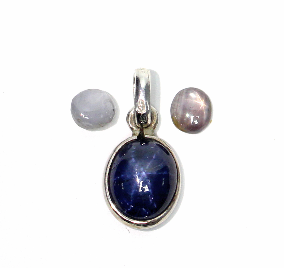 An oval blue star sapphire pendant; & two small un-mounted star sapphires in pink & white.