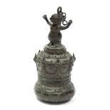 An Indian cast bronze bell with mythical beast forming the handle, & with all-over relief