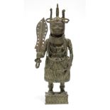 A Benin bronze standing figure of a warrior, holding a sword in one hand, on rectangular base;