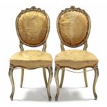 A pair of 19th century French cream & gilt painted salon chairs with foliate carving, the rounded