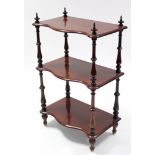 A Victorian mahogany three-tier serpentine-front whatnot on turned supports with pointed finials;