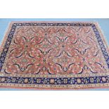 A Persian carpet of peach, ivory, & deep blue ground, with four rows of fine floral spandrels within