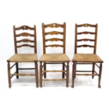 Three oak ladder-back dining chairs, each with woven-string seat, & on turned legs with turned