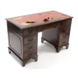 A reproduction mahogany pedestal, desk fitted with an arrangement of eight drawers, & on bracket