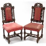 A pair of Victorian carved oak side chairs with padded backs & sprung seats, & on turned legs with