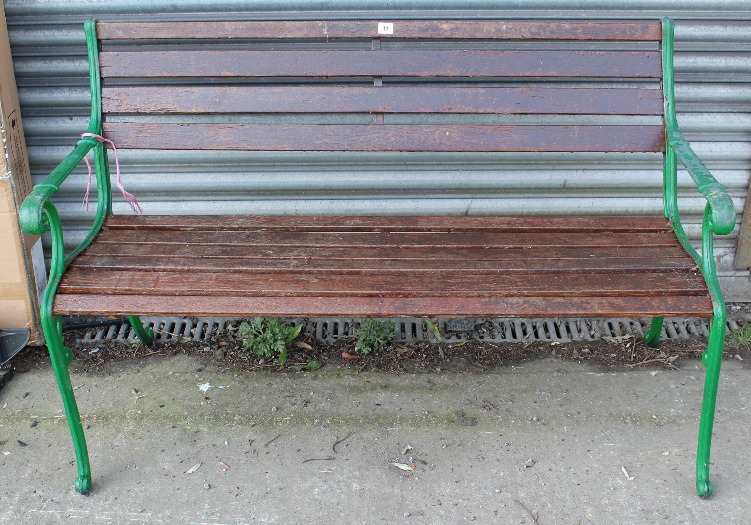 A teak slatted garden bench with green painted cast-iron end supports, 49½” long.